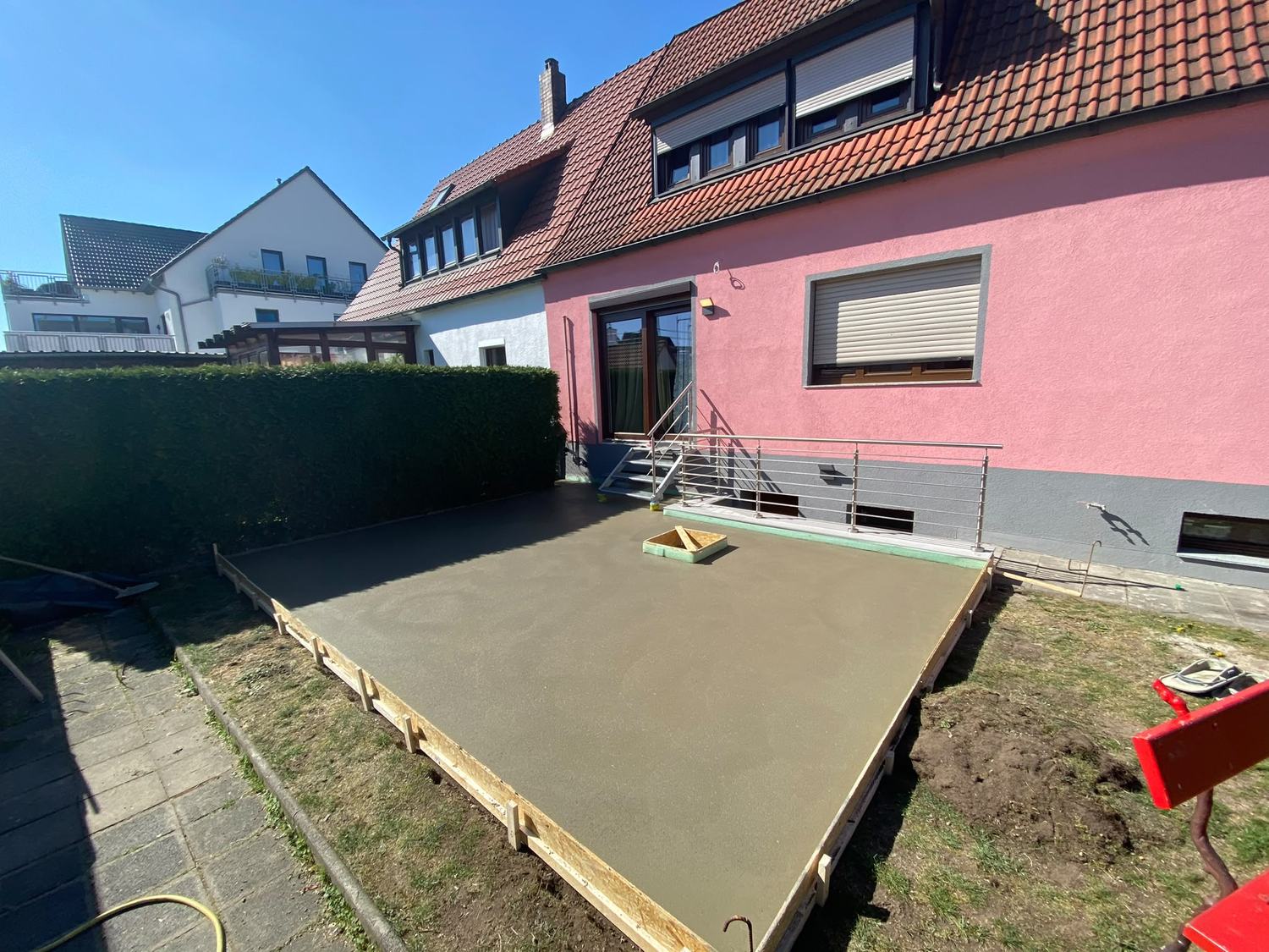 Abgezogene Außenfläche mit Schalung vor einem Wohnhaus
