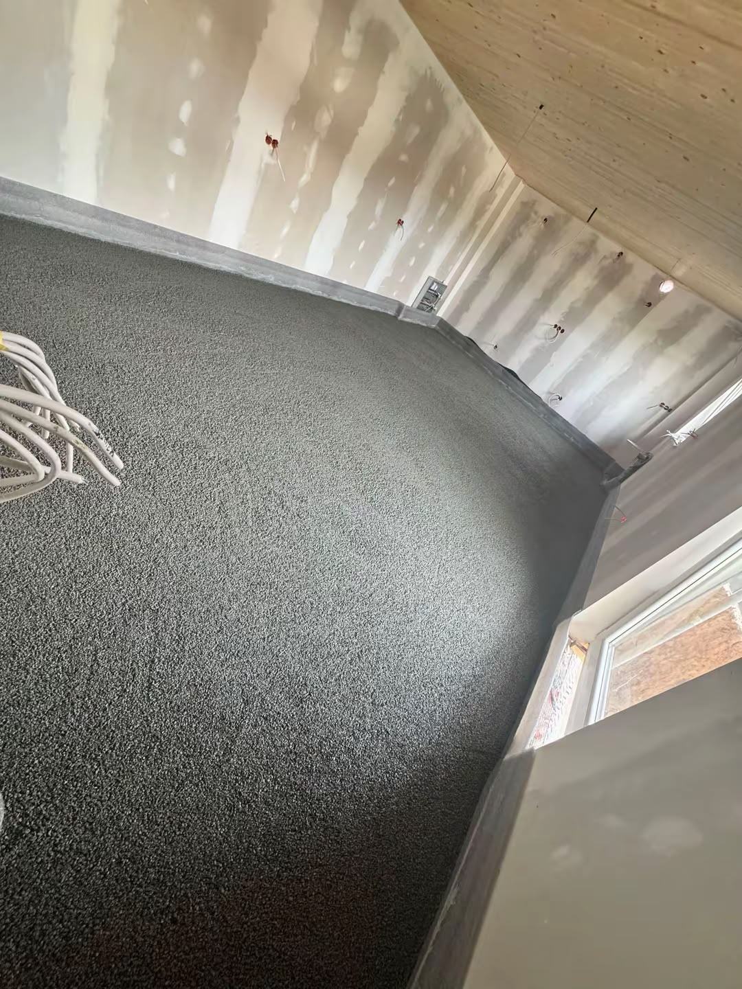 Graue Schüttung in einem Dachgeschoss, am Rand die Leitungen