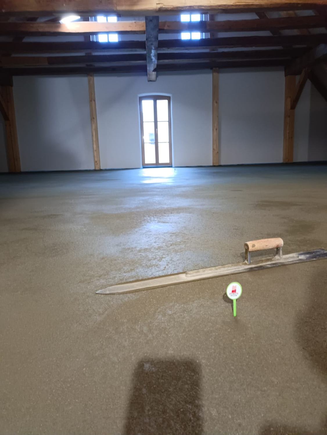 Frisch abgezogene Fläche in einem Dachboden mit Glättkelle und Markierung von Estrich Vilen