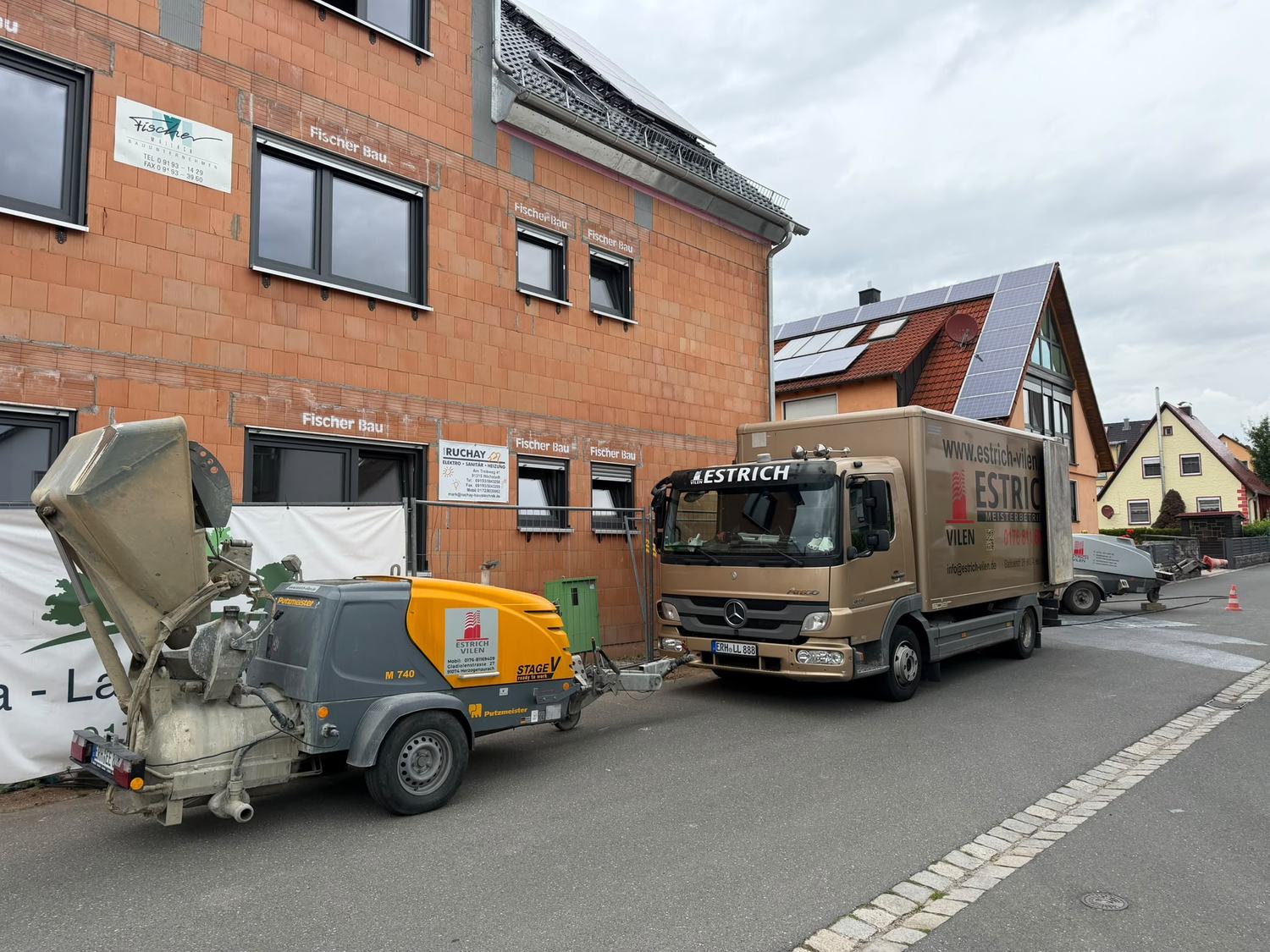 Estrichpumpe und Lkw von Estrich Vilen vor einem Neubau